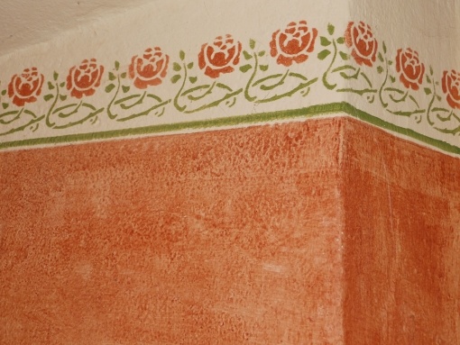 Wandlasur in Wischtechnik auf Lehmputz mit zweifarbiger Schablonierung „tanzende Rose“